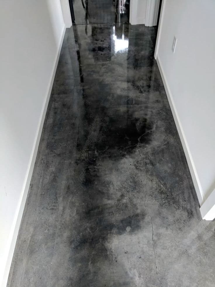 Narrow hallway demonstrating a high-gloss, dark tinted polished concrete floor with natural mottling.