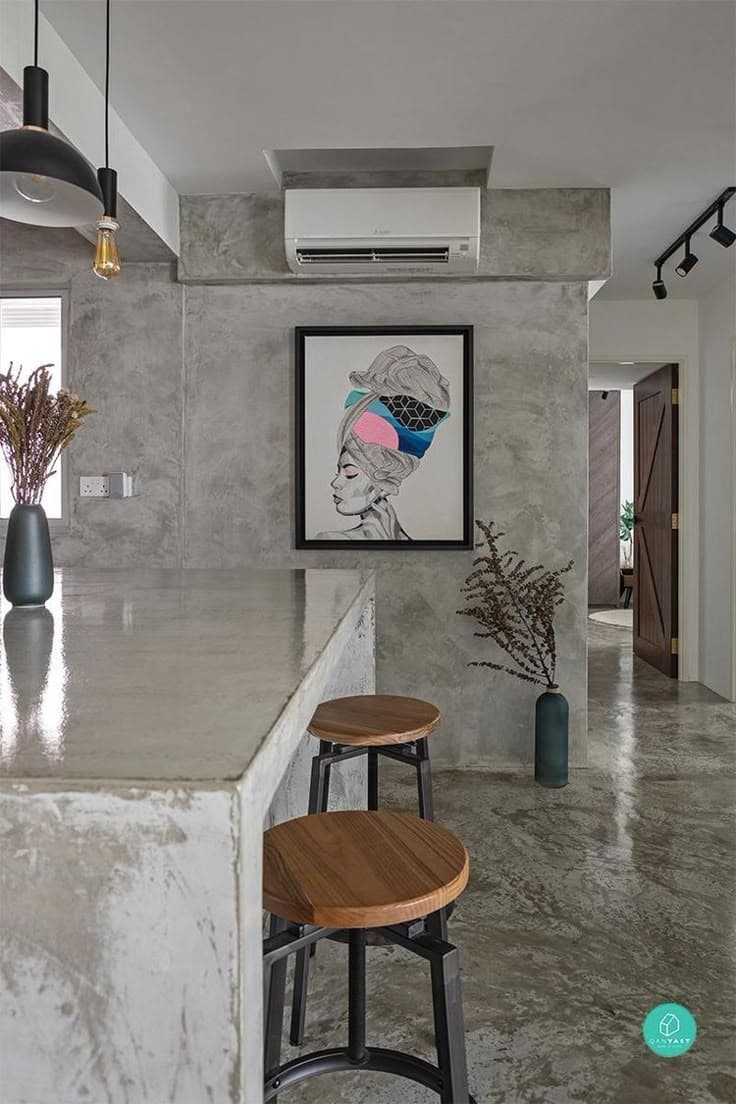 Modern home interior featuring a seamless polished concrete floor, concrete island, and wooden bar stools.