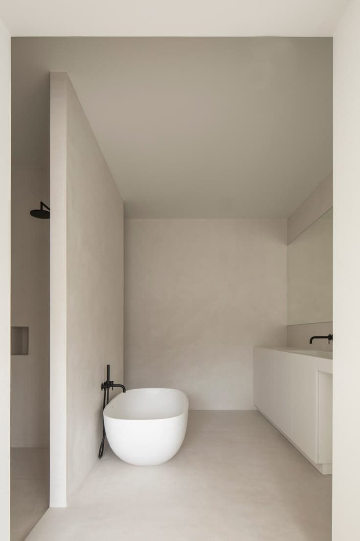 Luxury microcement bathroom featuring a white freestanding bathtub and seamless walls