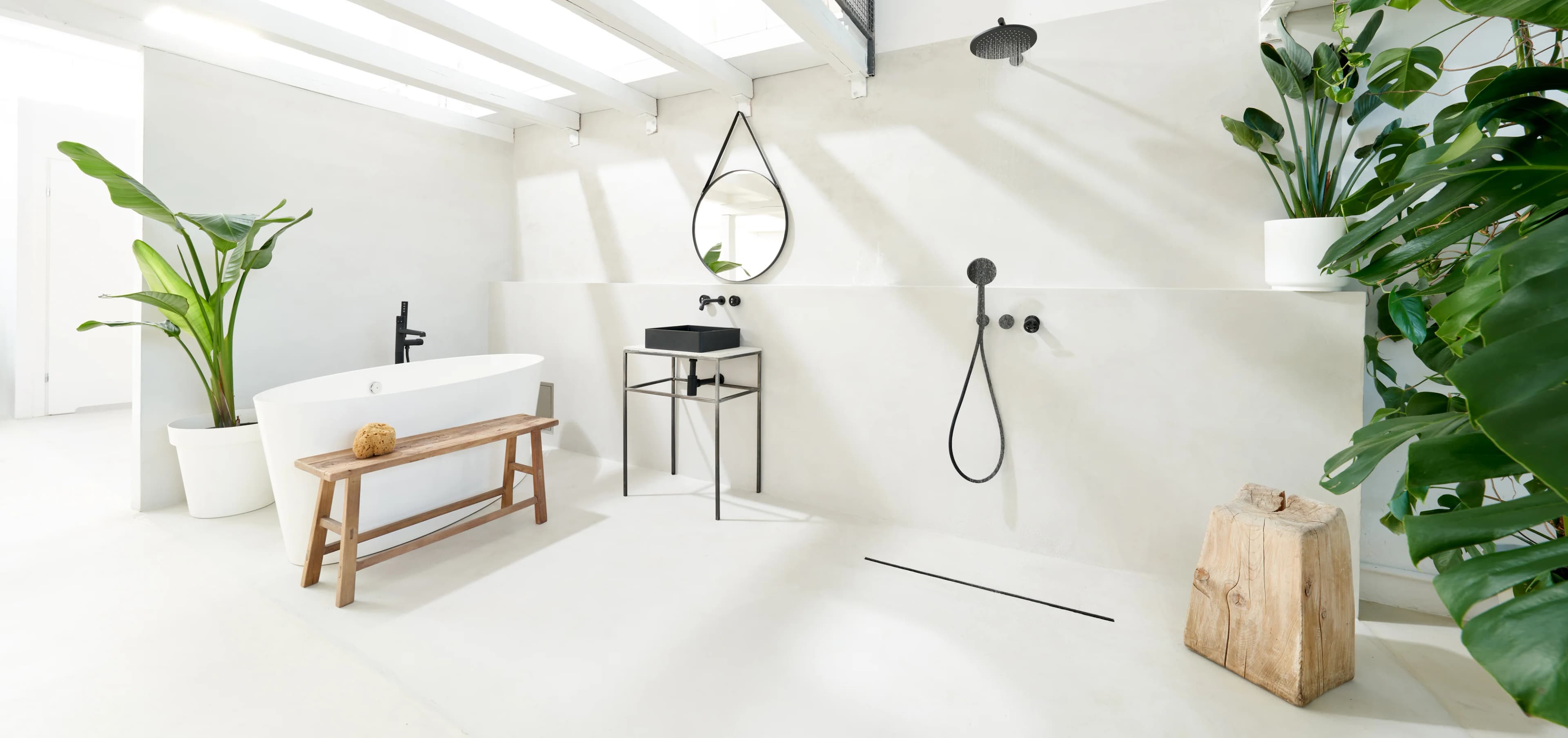 Luxury spa-style bathroom in Riyadh featuring a monolithic white microcement finish on floors and walls, showcase a grout-free, waterproof wet room with a freestanding tub and walk-in shower.