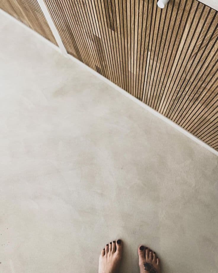 Cream Oatmeal microcement texture on a kitchen floor, showcasing a warm, light-reflecting mineral finish paired with wood accents.
