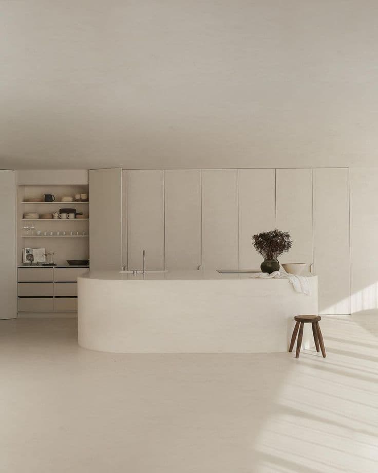 Large oval-shaped white microcement kitchen island, providing a grout-free and hygienic surface for food preparation.