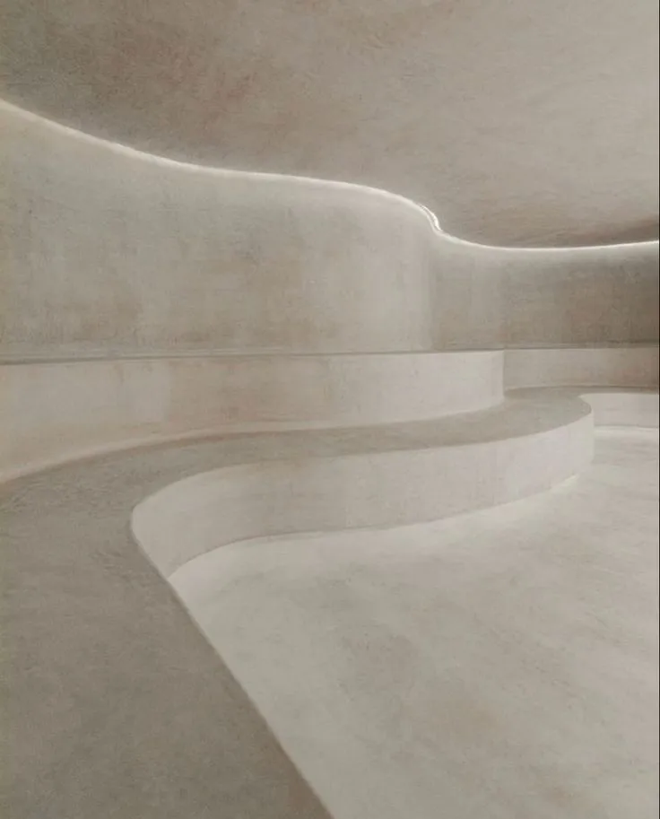 Modern living room feature wall in grey microcement, acting as a dramatic focal point with a non-repeating textured mineral finish.