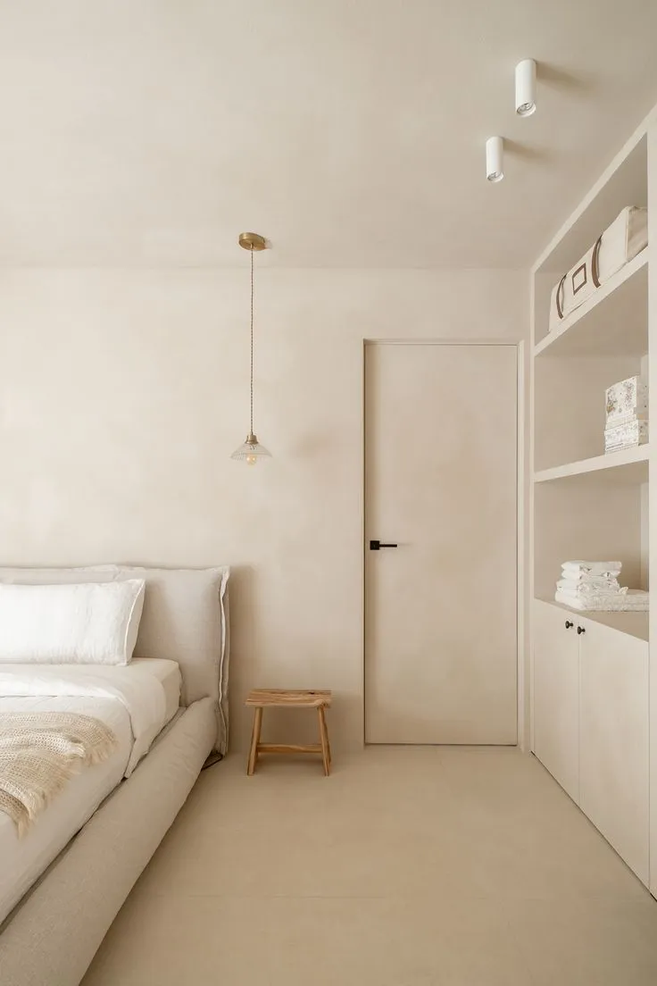 Modern bedroom with monolithic microcement walls and integrated storage.