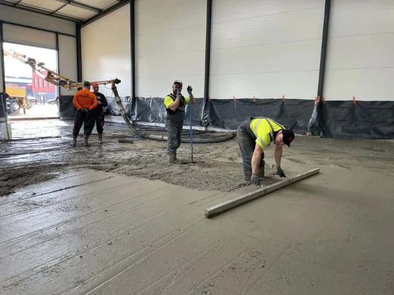 Workers pouring and leveling fresh concrete flooring in Saudi Arabia