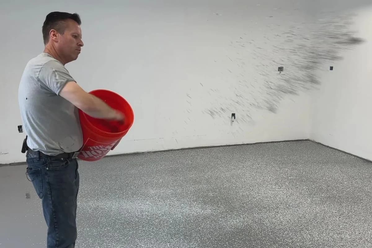 Floroz worker broadcasting decorative vinyl flakes onto wet epoxy base coat for flooring in Saudi Arabia