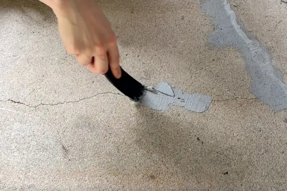 Floroz hand applying epoxy mortar to repair cracks before primer application on concrete garage floor in Dammam, Saudi Arabia
