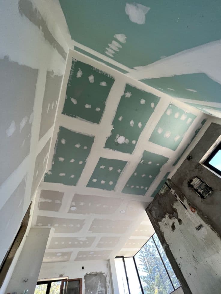 Precision gypsum board installation in a modern office space showing stud framing and board layers