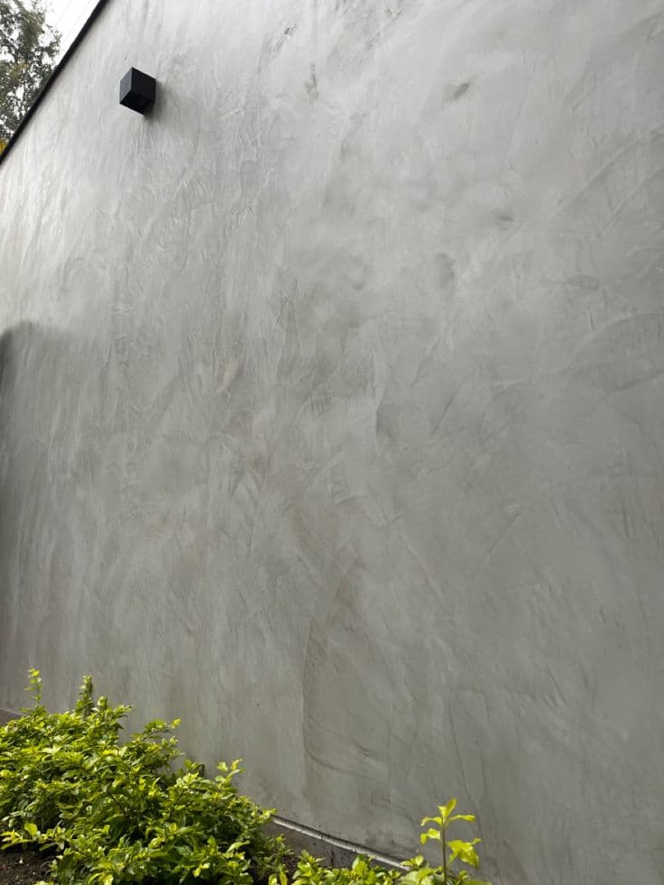 Detailed view of hand-troweled grey microcement exterior wall showing artisanal mineral texture