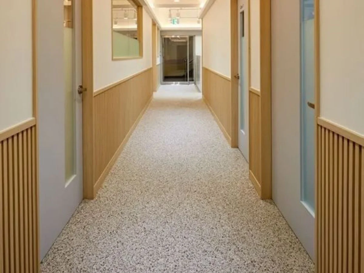 Exterior terrazzo in a covered walkway with anti-slip aggregate texture and drainage channels