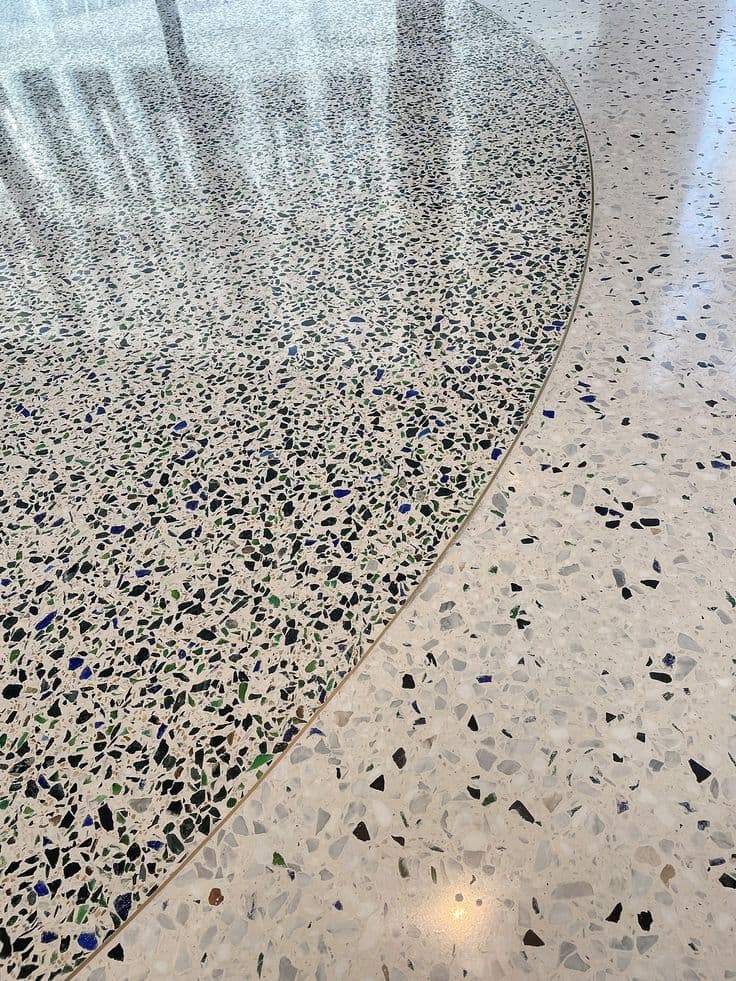 Polished marble chip epoxy terrazzo flooring in a luxury hotel lobby with decorative brass dividers