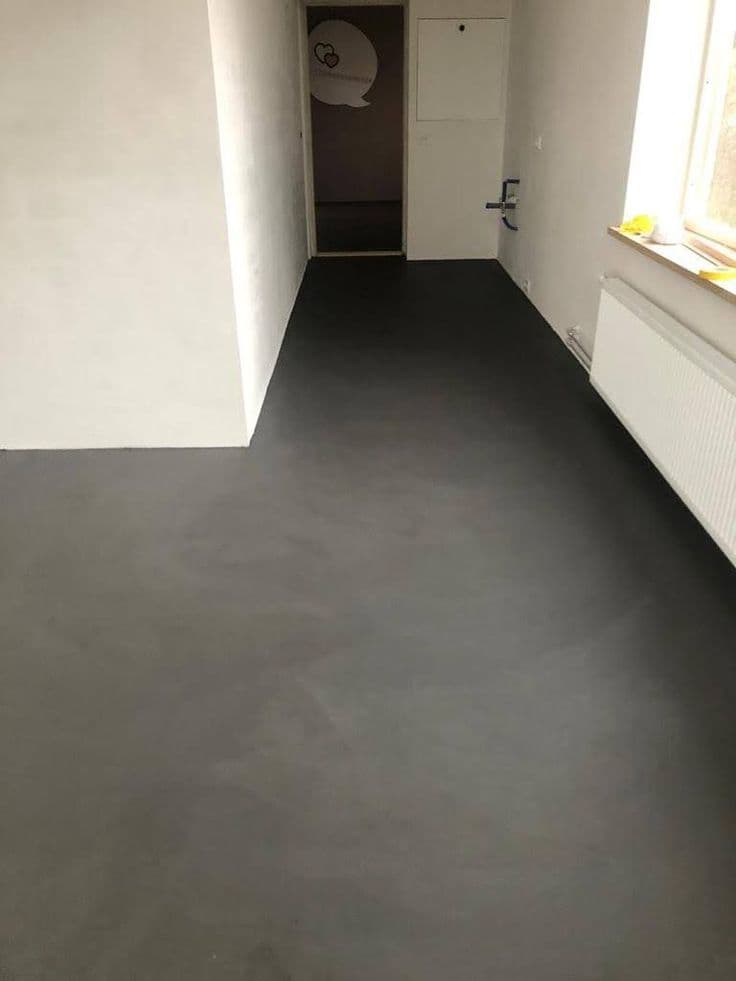 High-density dark grey microcement flooring installed in a residential hallway showing a monolithic matte finish.