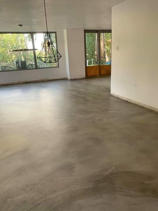 Industrial-grade microcement flooring with a natural concrete aesthetic in a large, light-filled modern interior.