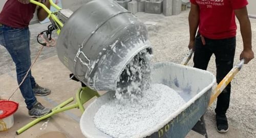 Workers mixing and pouring terrazzo with marble chips in a Jeddah construction site, preparing for durable flooring in Saudi Arabia’s humid climate.