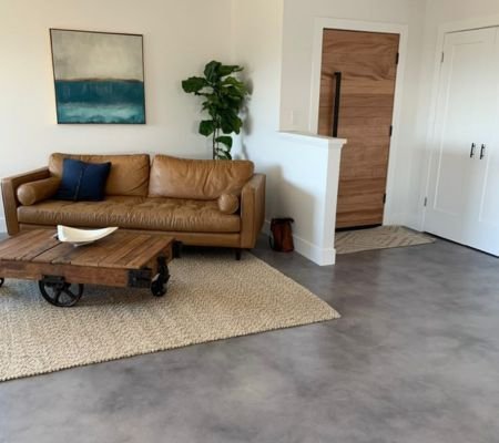 Modern concrete flooring in a living room with a brown leather sofa and wooden coffee table in Saudi Arabia
