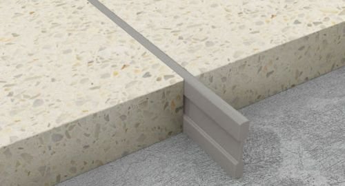 Installing metal divider strips on a subfloor for terrazzo flooring in a Riyadh construction site, ensuring heat-resistant patterns.