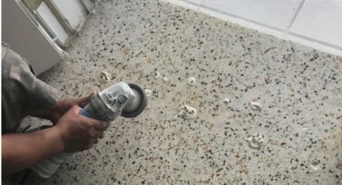 Worker grinding terrazzo floor with a machine in a construction site