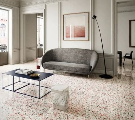 Modern Saudi living room with white terrazzo flooring, curved grey sofa, and minimalist coffee table in Riyadh