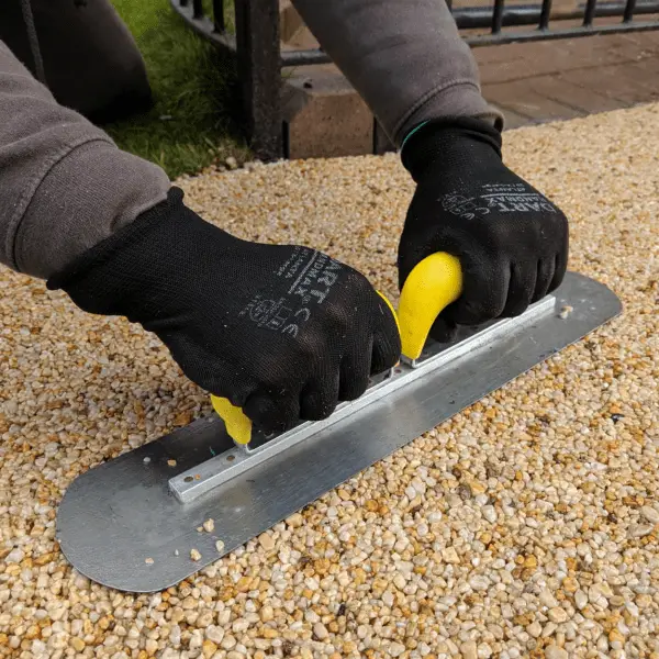 Hand-screeding resin-bound against a depth gauge to preserve the 20% void structure