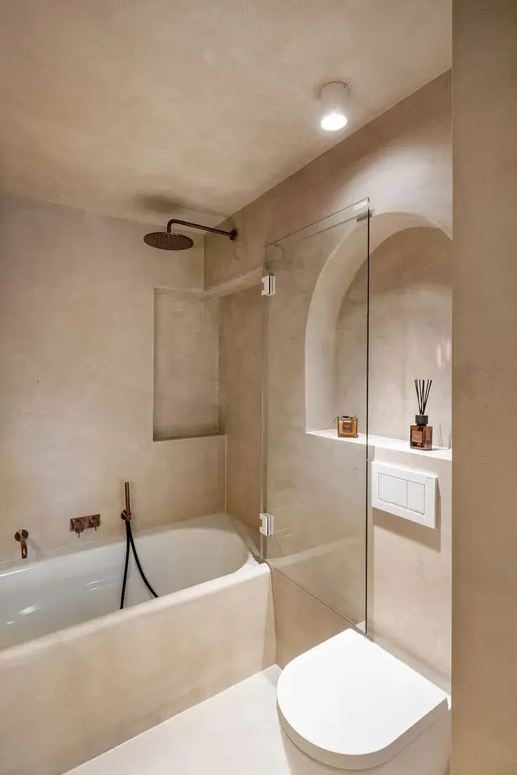 Bright minimalist bathroom featuring continuous light microcement surfaces on floor and walls.