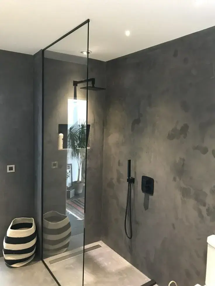 Modern waterproof wet room featuring continuous microcement floor-to-wall surfaces and a walk-in shower.