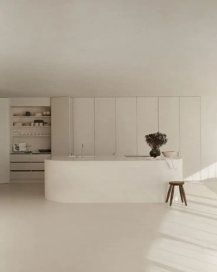 Oval white microcement kitchen island providing a grout-free and hygienic food preparation surface.