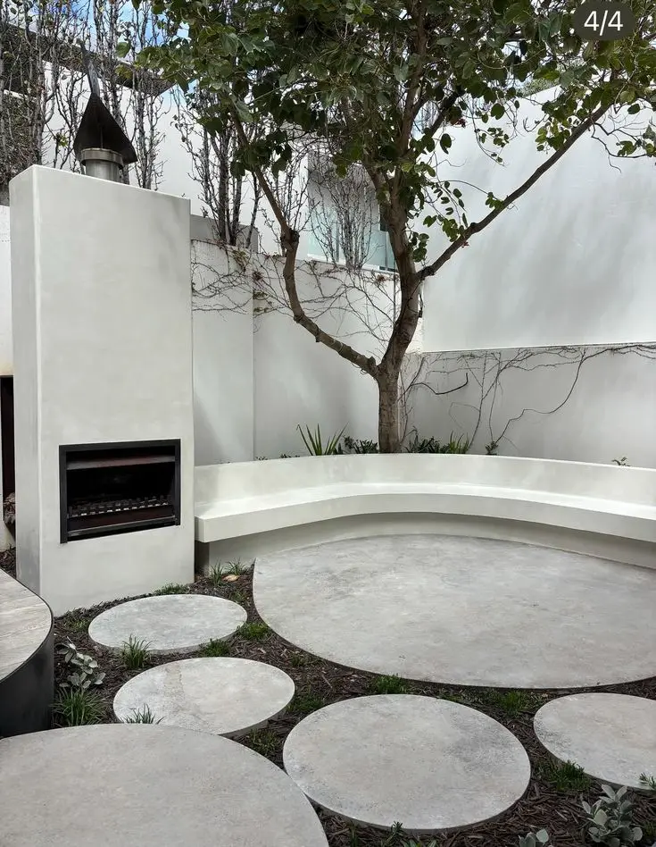 White seamless microcement outdoor patio with curved bench wall and circular stepping elements