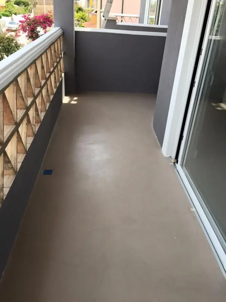 Warm beige seamless microcement applied directly over existing balcony surface with no grout lines