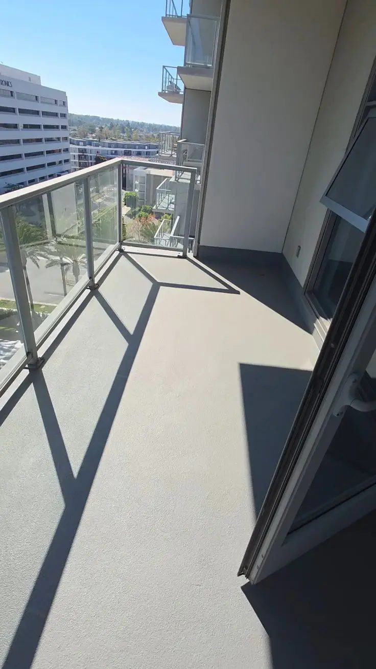 Grey seamless microcement balcony floor with anti-slip finish and open city view