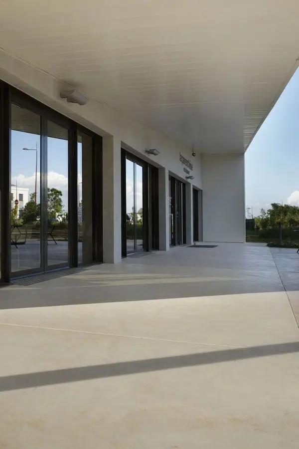 Seamless microcement floor on covered outdoor facade with large glass doors and no joints